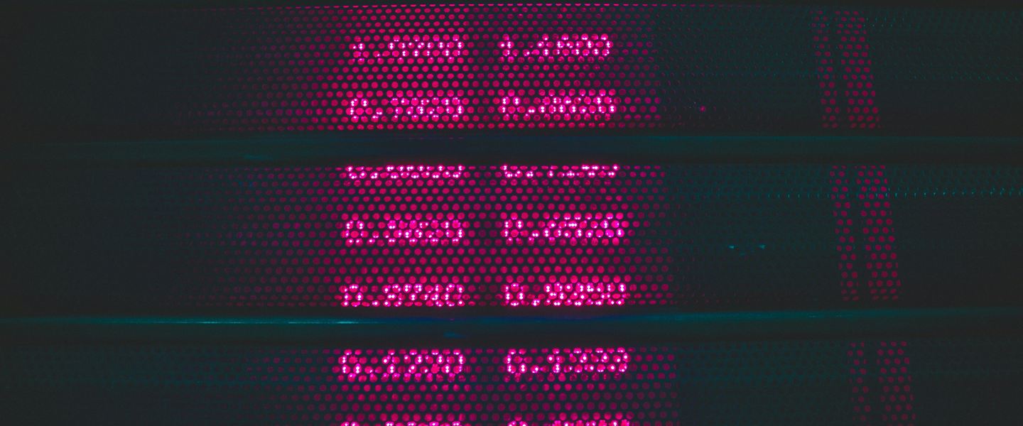 Rows of glowing pink figures on a dark electronic rate board