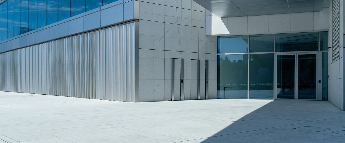 Glass entrance of a modern office building across an empty stone forecourt