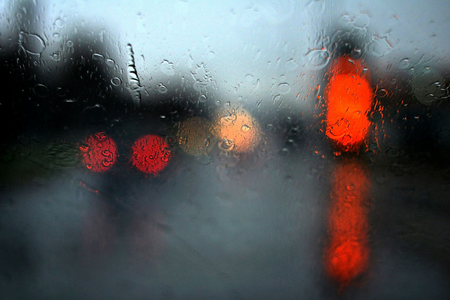 Rain on a windscreen with red traffic and brake lights blurred beyond