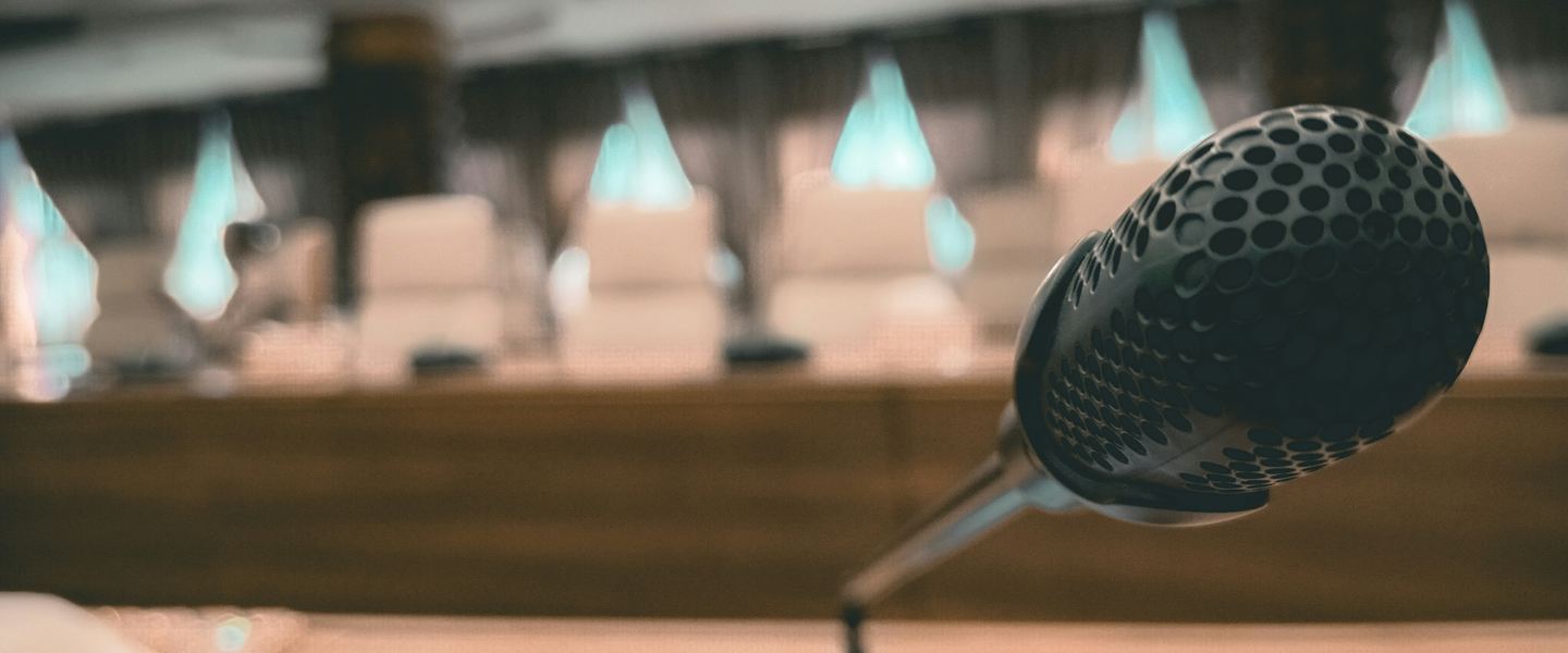 Desk microphone in a meeting chamber with rows of empty seats behind