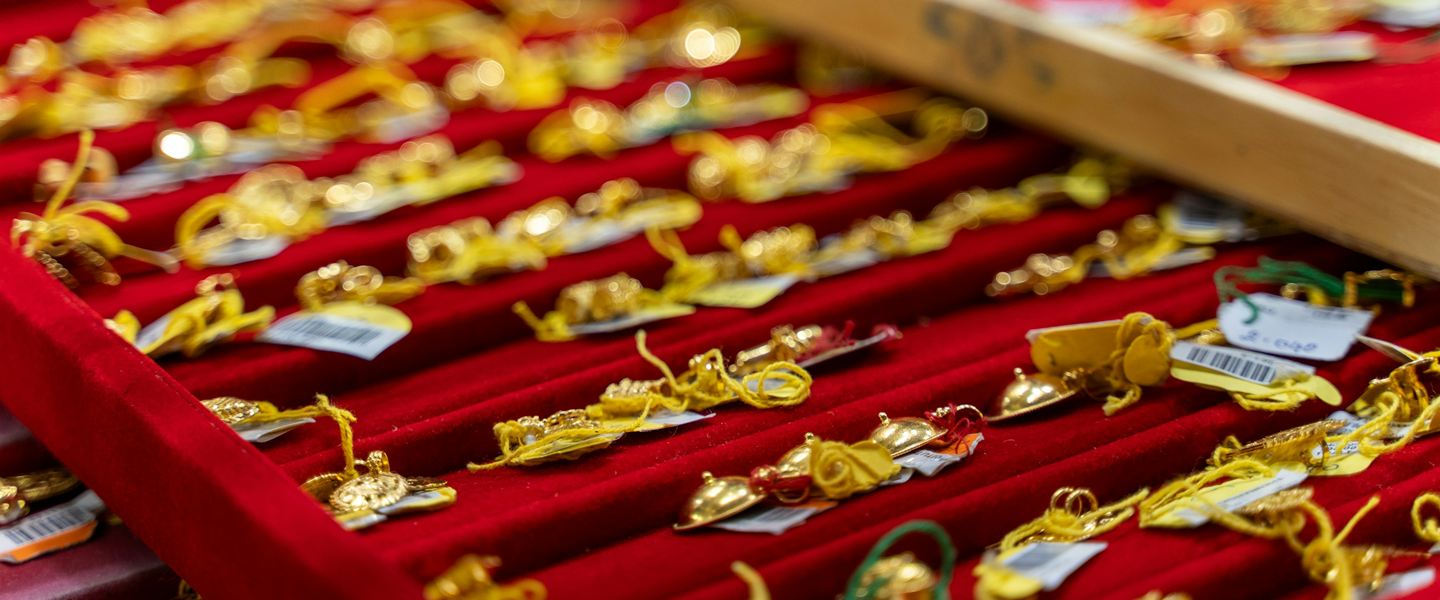 Gold pendants with price tags laid out on red velvet trays