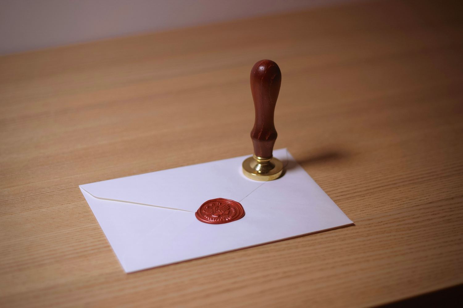 Wooden-handled seal stamp and a red wax seal on a white envelope