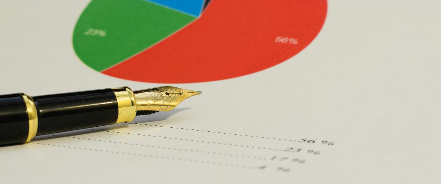 Fountain pen resting on a printed pie chart with percentage figures