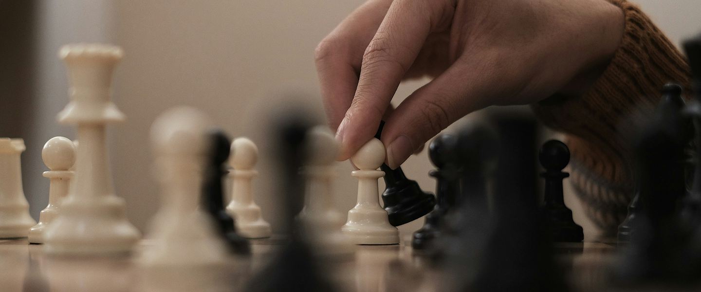Hand moving a white pawn on a chess board mid-game
