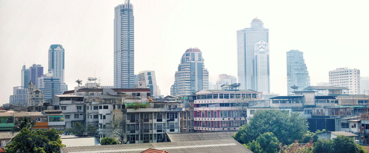Old low-rise houses and shophouses with Bangkok's office towers rising behind