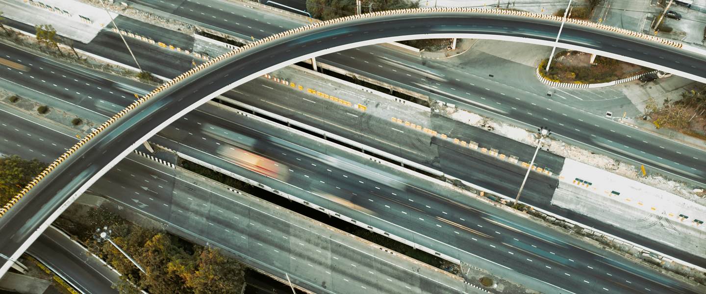 Curving flyover crossing a multi-lane expressway junction, seen from above