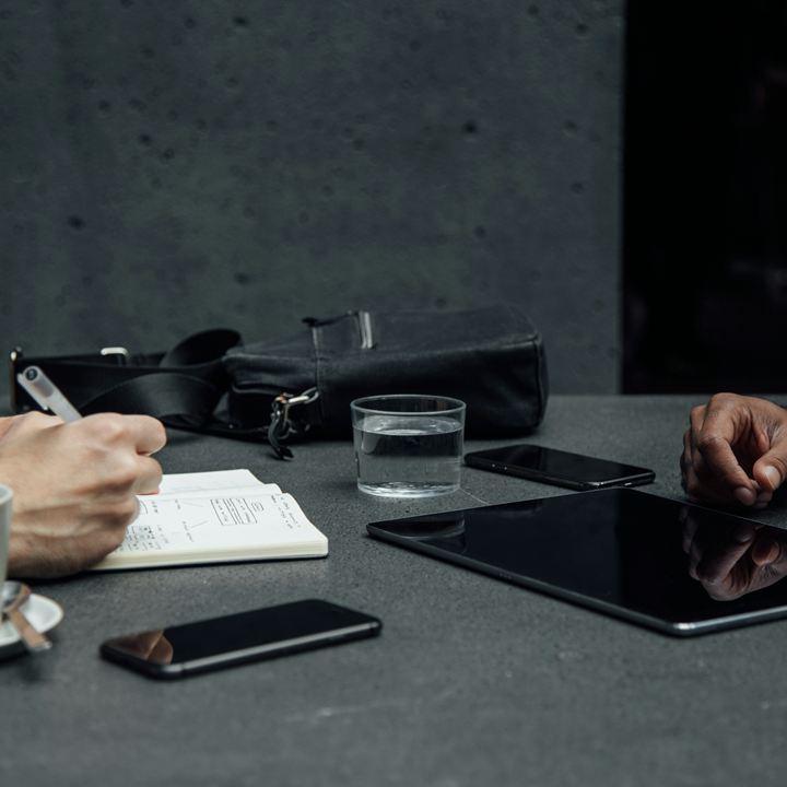 Two people talking across a table, one taking notes in a notebook
