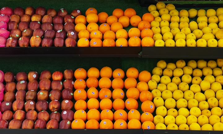 Rows of apples, oranges and lemons on a supermarket fruit display