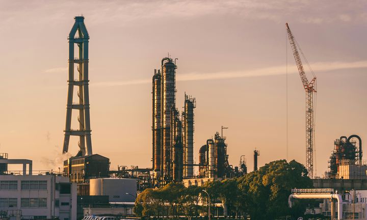 Refinery columns and a crane against an orange evening sky