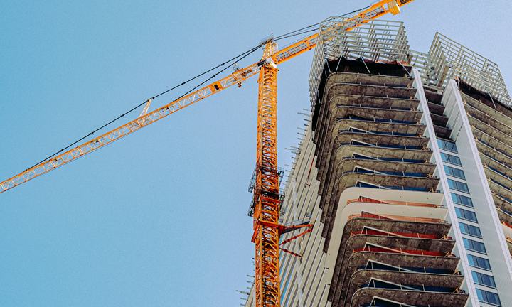 Tower crane beside a high-rise building under construction against a blue sky