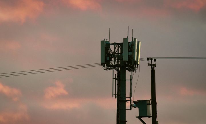 Mobile phone mast with antennas against a pink evening sky