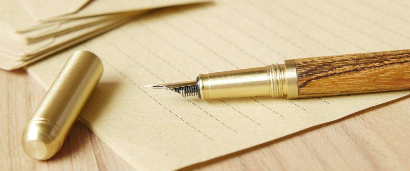 Fountain pen resting on lined paper beside a stack of envelopes